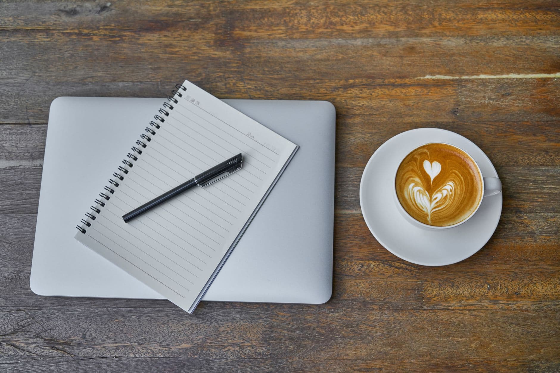 Skriver om privatøkonomi på laptop med notatbok og kaffe